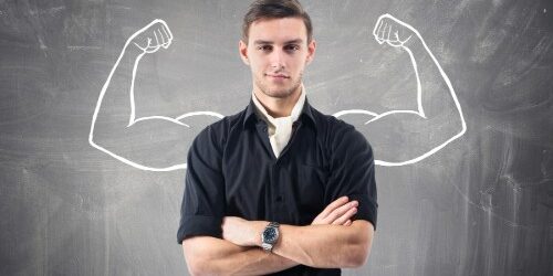 Strong Man standing in front of chalkboard with strong muscles flexing drawn in behind him