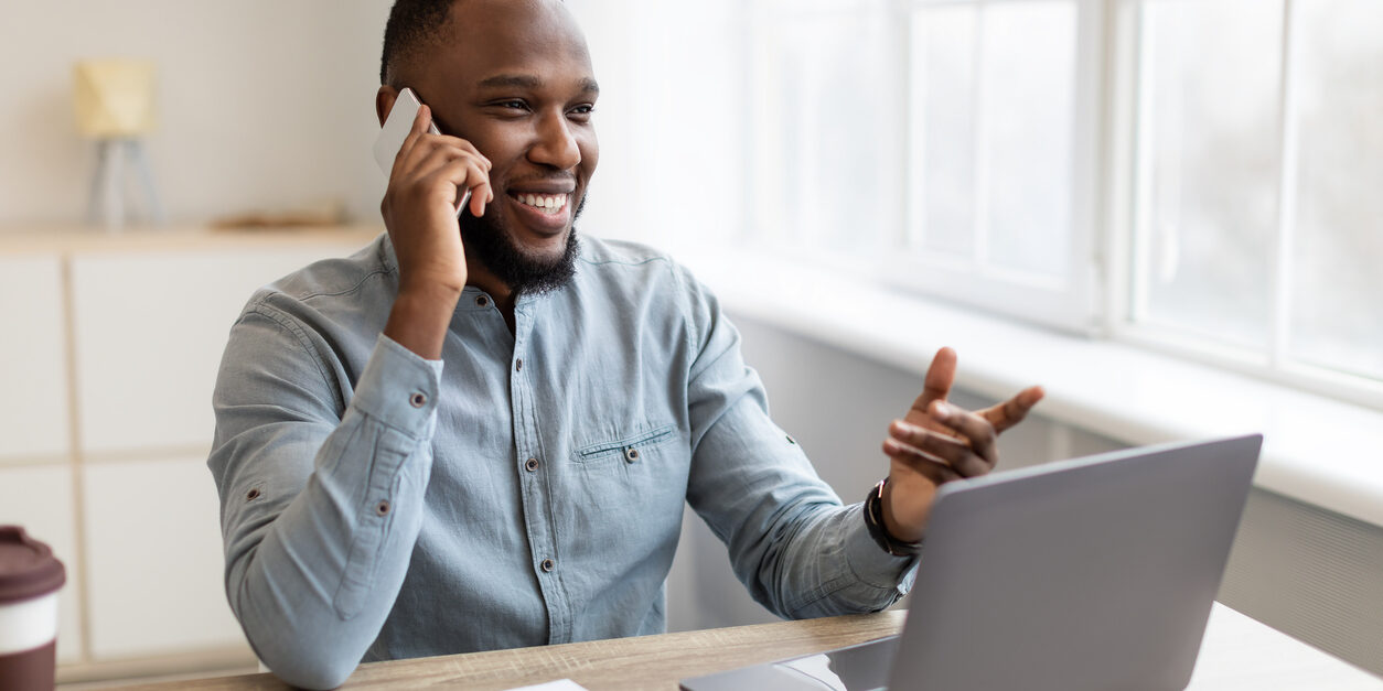 African American Businessman Talking On Mobile Phone Sitting At Workplace