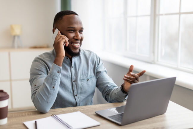 African American Businessman Talking On Mobile Phone Sitting At Workplace